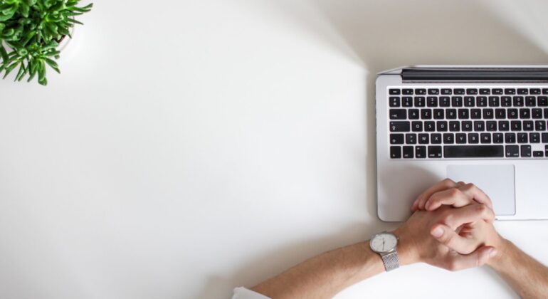 mac laptop with hands on it on the white table