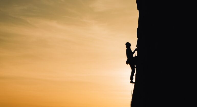man climbing vertically a mountain