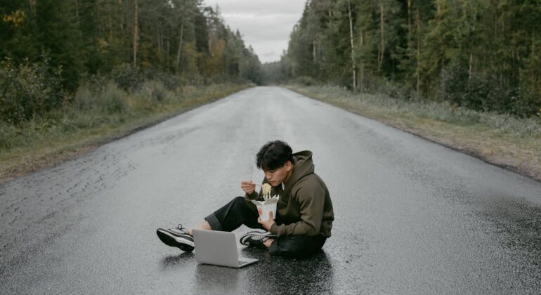 man working with a laptop while sitting on the road