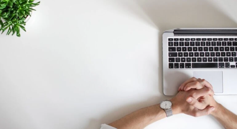 mac laptop with hands on it on the white table