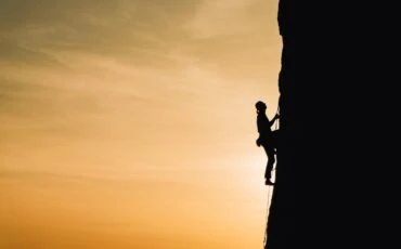 man climbing vertically a mountain