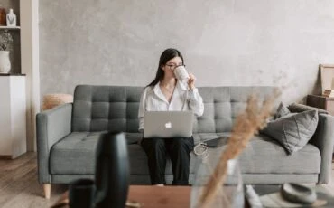 woman drinking coffee with a laptop sitting on the sofa