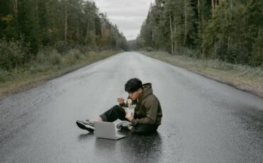 man working with a laptop while sitting on the road