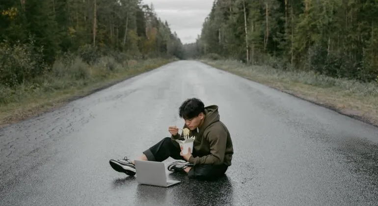 man working with a laptop while sitting on the road