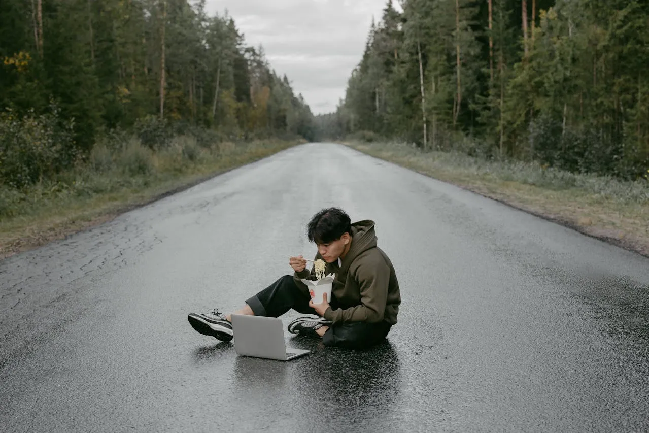 man working with a laptop while sitting on the road
