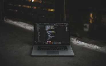 laptop with code on display on black background