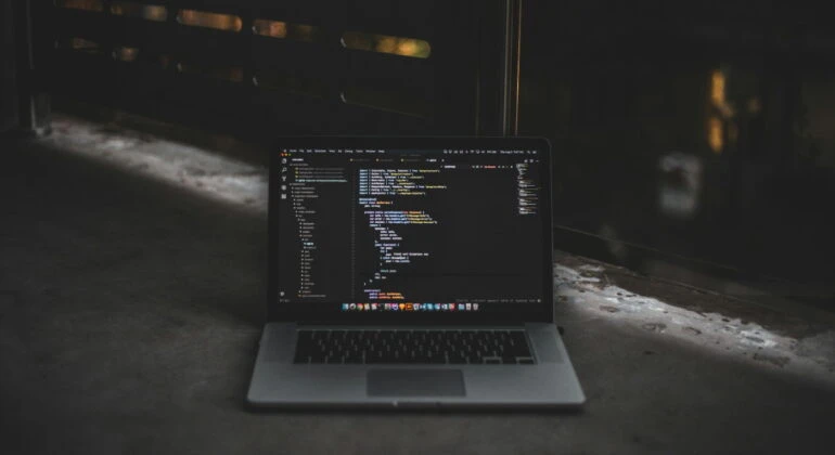 laptop with code on display on black background